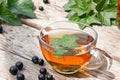 A cup of tea with black currant leaves. Tea with currants on a wooden table Royalty Free Stock Photo