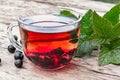 A cup of tea with black currants on a wooden table next to green leaves and currant berries Royalty Free Stock Photo