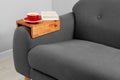 Cup of tea and book on sofa with wooden armrest table in room. Interior element Royalty Free Stock Photo