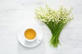 Cup of tea and bouquet of Lilies of the Valley on rustic table