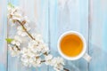 Cup of tea and branch of blossoming apricot on old wooden table