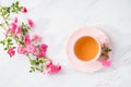 Cup of tea and branch of small pink roses on rustic table. Flat lay