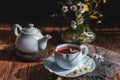 Cup of tea with chamomile flowers and a white teapot on a rustic wooden background. Rustic still life, authentic setting Royalty Free Stock Photo