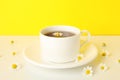 Cup tea and chamomile on white table against yellow background Royalty Free Stock Photo