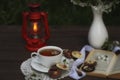 cup of tea with cherry blossom decoration on dark brown wooden background. Chokolate, bouquet, book and kerosene lamp Royalty Free Stock Photo