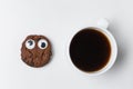 Cup of tea and chocolate chip cookie with funny face and Googly eyes. Coffee mug on white background top view Royalty Free Stock Photo