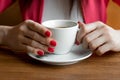 A cup of tea or coffee in the hands of a woman, pink manicure, close-up. The concept of cold weather Royalty Free Stock Photo