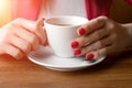 A cup of tea or coffee in the hands of a woman, pink manicure, close-up. The concept of cold weather Royalty Free Stock Photo