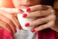 A cup of tea or coffee in the hands of a woman, pink manicure, close-up. The concept of cold weather Royalty Free Stock Photo