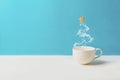 Cup of tea or coffee with steam in fir tree shape with gingerbread cookies on blue background. Christmas celebration concept. Copy
