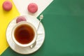 Cup of tea with colorful almond cookies on abstract yellow-green background with copy space Royalty Free Stock Photo