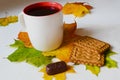 A cup of tea, cookies and chocolate candy lie on the table, among the autumn leaves on a white table Royalty Free Stock Photo