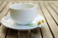 Cup of tea & Couple of wild daisy flower on a ceramic dish on wooden table