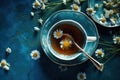 Cup of tea with daisies, chamomile and honey and spoons, top view, blue background. Royalty Free Stock Photo
