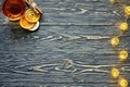 Cup of tea, dried slices of orange and cinnamon sticks with Christmas lights on a dark wooden background. Royalty Free Stock Photo