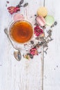 Cup of tea, dry rose button, french macaroons on the white wooden background Royalty Free Stock Photo