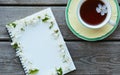A cup of tea and an empty notebook covered with cherry flowers. Blank space where you can put your text. Royalty Free Stock Photo