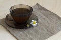 Herbal tea with chamomile flowers on sackcloth on a light wooden table