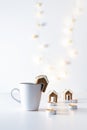 Cup of tea with gingerbread house and candles on white background. Christmas lights. Vertical frame Royalty Free Stock Photo