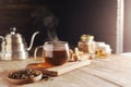 Cup or tea glass Hot brew and dried tea leaves on a wooden plate, placed on a wooden table, on a dark black background Royalty Free Stock Photo