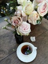 A cup of tea with Gorgeous bouquet of fresh roses on the table in the garden