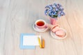 A cup of tea with heart shaped macarons, bouquet of forget-me-not flowers and card for congratulation text on a table