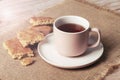 A cup of tea and homemade biscuits on sackcloth napkin on wooden table, closeup Royalty Free Stock Photo