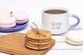 A cup of tea with the inscription Good luck, a stack of crispy cookies on a wooden cutting board and a plate of marshmallows in