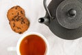 Cup of tea, iron teapot, and cookies on the white cloth background Royalty Free Stock Photo