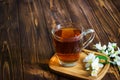 A cup of tea with jasmine flowers on brown wooden background