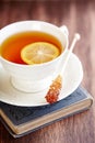 Cup of Tea with Lemon and brown Sugar Stick on a old Book. Royalty Free Stock Photo