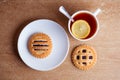 Cup of tea and lemon, cookies with jam in saucer on table top view