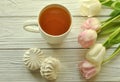 A cup of tea with lemon, fresh tulips and appetizing marshmallows Royalty Free Stock Photo
