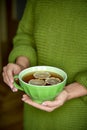 Cup of tea with lemon in hand, yellow autumn leaf.Warm drink concept.