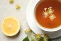 Cup of tea, lemon and linden blossom on grey marble table, flat lay