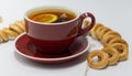 Cup of black tea bag with lemon and bagels.