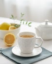 A cup of tea with lemon and a teapot on a white table against the background of a kitchen window close up Royalty Free Stock Photo