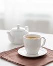 A cup of tea with lemon and a teapot on a white table against the background of a kitchen window Royalty Free Stock Photo