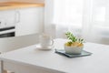 A cup of tea with lemon and a teapot on a white table against the background of a white kitchen with wooden countertop Royalty Free Stock Photo