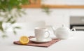 A cup of tea with lemon and a teapot on a white table with branch Royalty Free Stock Photo