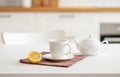 A cup of tea with lemon and a teapot on a white table. Kitchen with wooden empty countertop and brick wall in the background Royalty Free Stock Photo