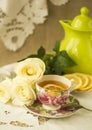 Cup of tea with lemon and white roses on an embroidered napkin