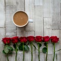 Cup of tea with milk and a row of red roses on a wooden board. Flat lay.