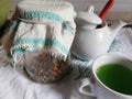 Cup of tea from natural herbs,a cup of green tea, a bowl of sugar and Grandma`s jars with natural herbs, flowers and roots dried a