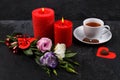 A cup of tea next to a candy on a heart, a bouquet of roses and burning roses on a stone background