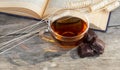 Cup of tea with open book and chocolate sweets on wooden background. Royalty Free Stock Photo
