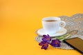 A cup of tea, a phone, purple crocus flowers on a gray napkin on a yellow background, a place for text