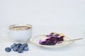 Cup of tea, piece of blueberry pie and blueberries on a white background - close up.