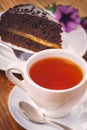 A cup of fresh hot tea with delicious piece of Sacher cake on the wooden table