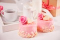 A cup of tea, pink roses, gift box and small cakes on the white table. Romantic concept